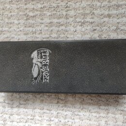 Černý obdélníkový předmět s texturovaným povrchem. Na levé straně je bílé logo s vyobrazením orla a nápisem ERNIE BALL. Povrch je v dobrém stavu bez…