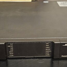 Černý rackový zesilovač s kovovým povrchem. Na předním panelu je vlevo nápis PSX1204D, uprostřed kontrolní panel s LED indikátory a vpravo logo BOSE…