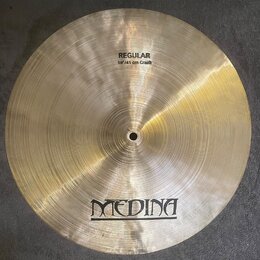 Zlatý kovový činel s viditelným kruhovým broušením povrchu. V horní části je nápis REGULAR a pod ním 16"/41 cm Crash. Ve spodní části je umístěno log…