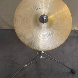 Zlatý kovový činel typu splash na černém stativu. Na povrchu je nápis "Paiste" a v dolní části označení "Splash 10"". Povrch činelu vykazuje jemné ko…