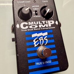 Černý efekt pedál s modrými vodorovnými pruhy. Na přední straně je bílý nápis MULTICOMP True Dual Band Compressor a logo EBS. Pedál má dva ovládací k…