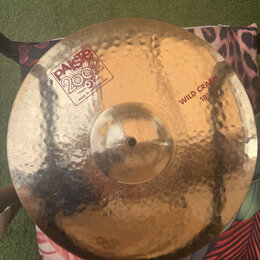 Kovový činel s kladeným povrchem v zlatavé barvě. Na povrchu je nápis „paiste 2002“ v obdélníkovém rámečku s doplňkem „TRADE MARK MADE IN SWITZERLAND…