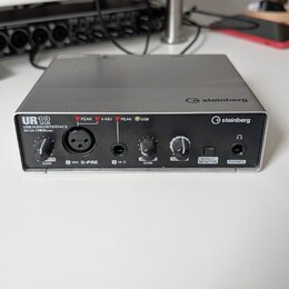 Stříbrná USB audio rozhraní s černým předním panelem. Na zařízení jsou nápisy UR12, USB AUDIO INTERFACE 24-bit / 192kHz a logo steinberg. Přední pane…