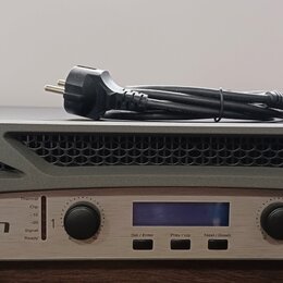 Šedý výkonový zesilovač s kovovým předním panelem stříbrné barvy. Na panelu je vlevo logo a nápis CROWN a vpravo označení 4002 XTi SERIES. Zařízení m…