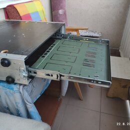 Stříbrný kovový rack s vysunutým šuplíkem. Vnitřek šuplíku je vyložen zelenou deskou s vyfrézovanými drážkami a otvory. Povrch horní desky racku je č…