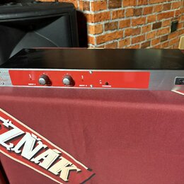 Černý rackový procesor s červeným předním panelem. Na levé straně je bílý nápis „X2“ a pod ním menší text „SOUND PROCESSOR“. Panel obsahuje dva ovrat…