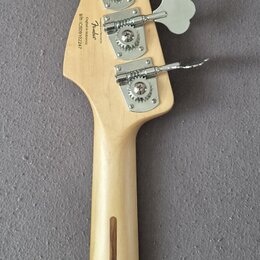 Zadní strana hlavy a krku světlé dřevěné basové kytary. Na hlavě jsou čtyři kovové ladičky a nápisy „Fender“, „Custom Offset“, „Made in USA“ a sériov…
