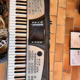 Stříbro-černý digitální klavír s bílými a černými klávesami. Na přístroji jsou viditelný nápisy Roland a E-60 MUSIC WORKSTATION. Povrch vykazuje znám…