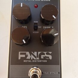 Černý efekt pedál s kovovým tělem a čtyřmi ovládacími knoflíky. Na povrchu jsou nápisy „tc electronic“, „FANGS METAL DISTORTION“ a „TRUE BYPASS“. Mez…