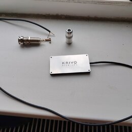 Na fotografii je stříbrný obdélníkový snímač s nápisem KRIVO PICK-UPS. K němu je připojen černý kabel, který končí kovovým jack konektorem. Vedle sní…