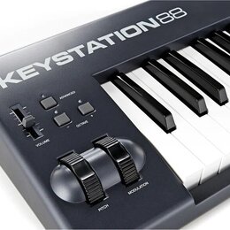 Detailní pohled na levou část černé MIDI klávesnice s bílými a černými klávesami. Na horní hraně je bílý nápis KEYSTATION88. Ovládací panel obsahuje…