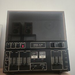 Černý cívkový magnetofon s průhledným plastovým krytem. Na předním panelu je nápis TESLA B 113 a pod ním HIGH FIDELITY STEREO. Zařízení obsahuje něko…