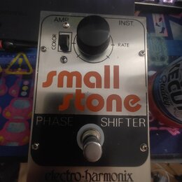 Kovový efekt pedál s nápisem small stone PHASE SHIFTER v oranžové a bílé barvě. V horní části je černý ovládací knoflík RATE, přepínač COLOR s označe…