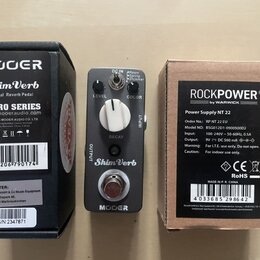 Fotografie zobrazuje efekt pedál Mooer ShimVerb v šedé barvě, jeho originální krabici a napájecí adaptér RockPower v krabici. Na pedálu jsou nápisy L…