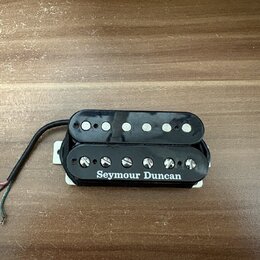 Černý humbucker s plastovým krytem a bílým rámečkem. Na boku je bílý nápis Seymour Duncan. Snímač má šest viditelných pólů, z nichž jedna řada je zak…