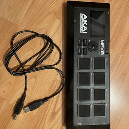 Černý sampler s osmi gumovými pady a displejem. Na přístroji jsou nápisy AKAI professional, MPX8 MOBILE SAMPLE PLAYER a označení 3D. K zařízení je př…