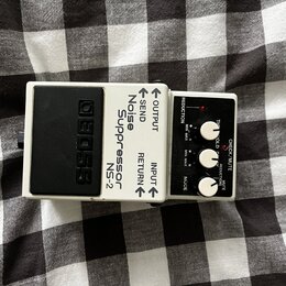 Bílý efekt pedál s černým stupňovitým šlapadlem. Na těle jsou nápisy BOSS, Noise Suppressor NS-2 a označení konektorů OUTPUT, SEND, RETURN, INPUT. Ov…