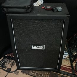 Černý basový nebo kytarový kombozesilovač s bílým rámečkem kolem textilní masky, na které je umístěno logo Laney. Na horní části přístroje leží černý…