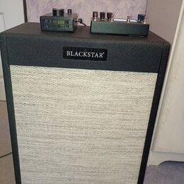 Černý kytarový kombozesilovač s bílým textilním krytem reproduktoru. Na horní hraně je umístěn černý štítek s bílým nápisem BLACKSTAR. Na horní ploše…