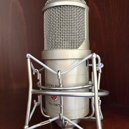 Stříbrný kondenzátorový mikrofon v pavoucím držáku. Na těle mikrofonu jsou nápisy LAUTEN AUDIO a FC-357. Povrch je v dobrém stavu bez viditelného opo…