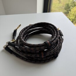 Svijený instrumentální kabel s černým opletením a červenými detaily. Na kabelu jsou viditelné nápisy "Roland" a "RIC-05BA". Konce kabelu tvoří zlaté…