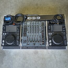 Sada DJ equipmentu v transportním kufru. Uprostřed je černý mixážní pult s nápisy ALLEN&HEATH a xone, po stranách jsou dva identické černé přehrávače…