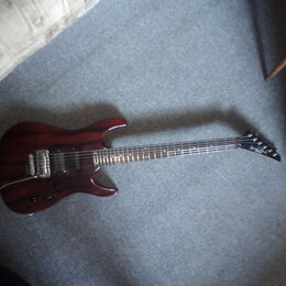 Elektrická kytara s tmavě červeným lakovaným trupem z dřeva s viditnou strukturou zrn. Nástroj má dva humbuckery, jeden tónový potenciometr a přepína…