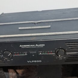 Černý výkonový zesilovač s nápisem AMERICAN AUDIO PROFESSIONAL POWER AMPLIFIER a označením modelu VLP600. Přední panel obsahuje dva ovratné ovládací…