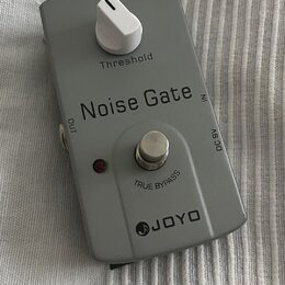 Šedý efekt pedál s bílým ovládacím knoflíkem. Na krytu jsou nápisy „Threshold“, „Noise Gate“, „OUT“, „IN“, „DC 9V“ a „TRUE BYPASS“. Ve spodní části j…