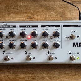 Stříbrný efektový procesor s nápisy T-REX a MAGNUS by TREX ENGINEERING Denmark. Zařízení obsahuje pět sekcí s ovládacími knoflíky a přepínači, označe…
