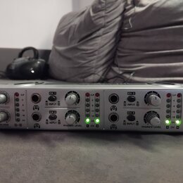 Stříbrný sluchátkový zesilovač s nápisy Mini AMP a 4-CH HEADPHONE AMP. Na předním panelu jsou ovládací knofíky, vstupy A INPUT B pro kanály CH 1 až C…