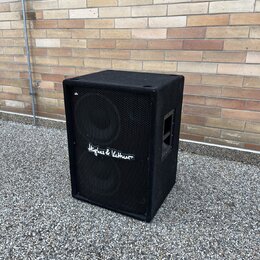 Černý reproduktor v hranatém korpusu s povrchem z textilie. Přední strana je kryta kovovou síťkou, na které je bílý nápis „Hughes & Kettner“. Povrch…