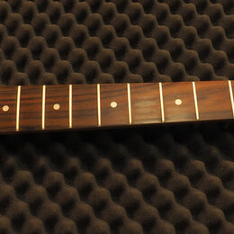 Hmatník elektrické kytary z tmavého dřeva s bílými polohovými značkami. Světle žlutá hlava kytary nese nápisy Squier a STRATOCASTER, v dolní části je…