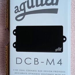 Fotografie znázorňuje černý snímač do basové kytary v originálním bílém obalu. Na obalu je nápis aguilar a modelové označení DCB-M4 spolu s popisem t…