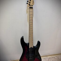 Elektrická kytara s černým průsvitným lakem, pod kterým je vidět struktura dřeva. Na hlavě hmatníku je černý nápis "Schecter". Nástroj má světlý hmat…