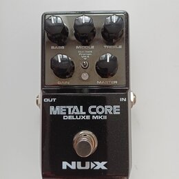 Černý kytarový efekt s nápisy METAL CORE a DELUXE MKII. V horní části jsou pět kontrolních knoflíků s popisky BASS, MIDDLE, TREBLE, GAIN a MASTER, př…