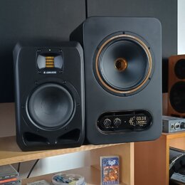 Na fotce jsou tři studiové monitory. Nejlevý vlevo je černý s nápisem ADAM AUDIO, prostřední je větší černý reproduktor s nápisy GOLD A a TAMPET v do…