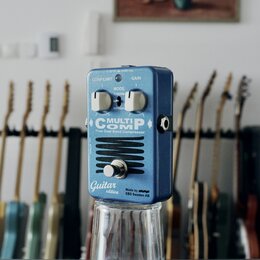 Modrý efekt pedál s kovovým povrchem. Na přední straně jsou nápisy MULTICOMP, True Dual Band Compressor, Guitar edition a Made by EBS Sweden AB. Pedá…