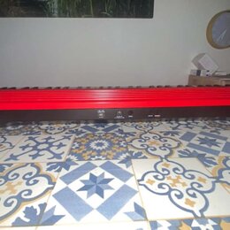 Červený digitální klavír s černým spodním panelem. Na levé straně je bílý nápis Roland a na pravé straně bílý nápis GO:KEYS. Nástroj je položen na vz…