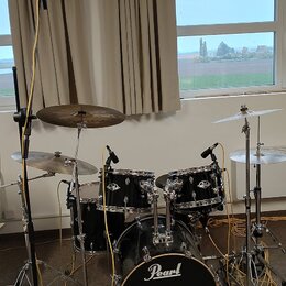 Černá bicí souprava značky Pearl s kovovým hardwarem. Sestává z basového bubnu s logem Pearl, dvou tomů, jednoho floor tomu a tří činelů. Nástroje js…