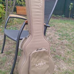 Hnědý polstrovaný obal na kytaru s úchytem a zipy. Na horní části je nápis GSmini, na přední kapse je logo Taylor obklopené nápisem QUALITY GUITARS.…