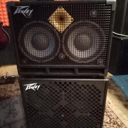 Dvě černé basové reprobedny naskládané na sebe, na nichž je umístěn černý zesilovač. Horní bedna má nápis Peavey a dva velké reproduktory s horním žl…