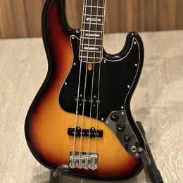 Elektrická basová kytara s korpusem v barevném přechodu od žluté přes oranžovou k červené a černé. Nástroj má černý pickguard, dva snímače a čtyři ov…