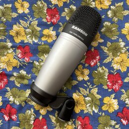Stříbrný kondenzátorový mikrofon s černou mřížkou a černým držákem. Na horní části je bílý nápis SAMSON a pod ním menší text C01 STUDIO CONDENSER. Po…