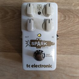 Bílý efekt pedál s nápisy SPARK BOOSTER a tc electronic. Na horní straně jsou čtyři bílé otočné ovladače s popisky BASS a TREBLE, doprovázené přepína…
