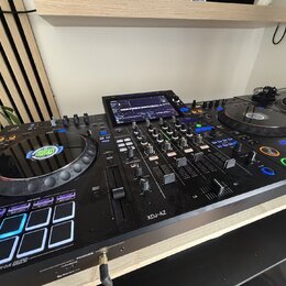 Černý DJ 컨트롤러 s integrovaným displejem a dvěma jog-koly. Na levém jog-kole je viditelné logo GRUCAST a na spodní části přístroje nápis XDJ-AZ. Zaříze…