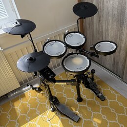 Elektronická bicí souprava černé barvy s bílými membránami. Na modulech a rámu je viditelný nápis Roland a na membránách označení V-Drums. Souprava o…