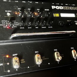 Černý kytarový procesor s nápisem POD HD300 a logem LINE 6 na přileženém pedálu. Zařízení má několik ovládacích knoflíků, digitální displej a pět sto…