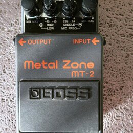 Černý efekt pedál s oranžovými nápisy Metal Zone a MT-2. Na spodní části je vyražené logo BOSS. Horní panel obsahuje čtyři ovládací knoflíky, červeno…