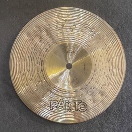 Zlatý cymbál typu splash s rýhovaným povrchem. Na nástroji je v dolní části velké logo PAiSte a nad ním nápis thin Splash 9". V horní části zvonu je…